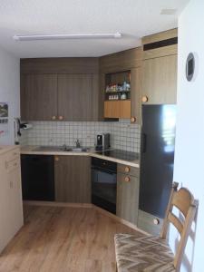 a kitchen with wooden cabinets and a black refrigerator at Bergblick 35 in Bolgen