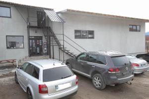 dos autos estacionados en un estacionamiento frente a un edificio en Cozy Rooms Toplita, en Topliţa