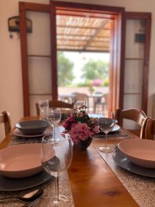 einen Tisch mit Tellern, Gläsern und Blumen darauf in der Unterkunft Villa Sara - Villa con piscina in Marina di Ragusa