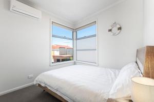 a white bedroom with a bed and a window at Bay and Relax in Apollo Bay