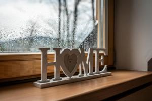 Ein Schild, auf dem steht, dass Liebe auf einem Fensterbrett sitzt. in der Unterkunft Aparteo Apartament Stojakówka in Kościelisko