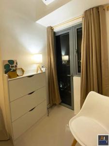 a bedroom with a dresser and a window with a lamp at Fame Residences Tower-1 Unit 3207 in Mandaluyong 1 Br w Balcony City view in Manila