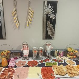 una tavola piena di alimenti con due statuine e piatti di alimenti di El Pozo de la Nieve a Tordesillas