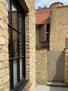 een stenen huis met een houten deur en een stenen muur bij Vis à Vis in Nieuwpoort