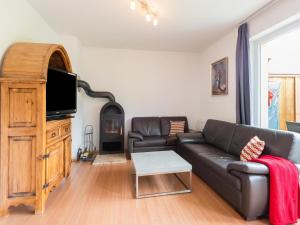a living room with a black leather couch and a tv at Wonderful holiday home in Kaprun Piesendorf with garden in Piesendorf