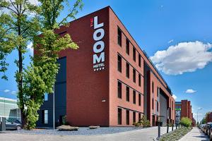 un edificio de ladrillo rojo con un cartel. en Hotel The Loom, en Łódź