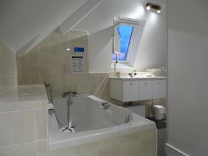 a white bathroom with a tub and a sink at La Granitiere Maison de Charme in Saint-Vaast-la-Hougue