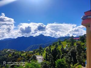 een uitzicht op een berg met een blauwe lucht en wolken bij Hotel Sunrise Inn & Restaurant, Kanatal in Chamba