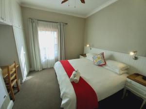 a bedroom with a bed with a teddy bear on it at 137 High Street Guest House in Grahamstown