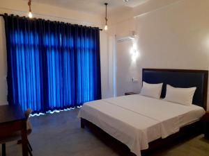 阿魯岡灣的住宿－Surf Gangs Arugambay，一间卧室配有一张带蓝色窗帘的大床