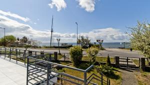 a walkway next to the beach with the ocean in the background at Apartamenty In Sea Bay Chałupy in Chałupy