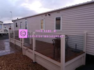 a mobile home with a deck with a sign on it at Seldongoldengates in Kinmel Bay