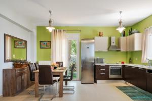 a kitchen with green walls and a stainless steel refrigerator at New Modern Villa Mirthios Panorama with Private Swimming Pool and BBQ! in Plakias