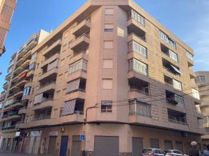 wysoki budynek apartamentowy z samochodami zaparkowanymi przed nim w obiekcie 062 - Club Náutico 005 - comfortHOLIDAYS w mieście Santa Pola +5 zdjęć