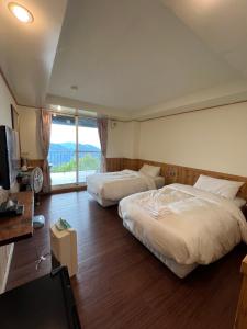 1 Schlafzimmer mit 2 Betten, einem TV und einem Fenster in der Unterkunft Cingjing Four Seasons B&B in Renai
