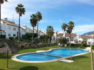 a swimming pool in a resort with palm trees and houses at Casa Adosada Bel Andalus in Estepona