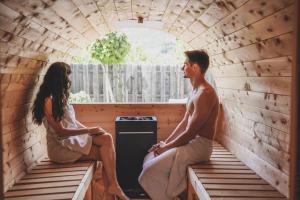 Un uomo e una donna seduti in una sauna di Residence Montani a Laces