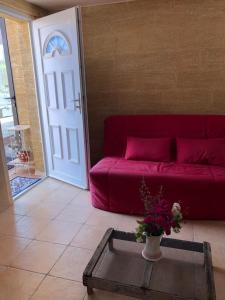 un divano rosso in soggiorno con tavolo di Mazet des lavandes a Saint-Quentin-la-Poterie