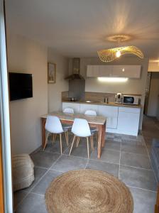 eine Küche mit einem Holztisch und weißen Stühlen in der Unterkunft Le Loutin in Saint-Bonnet-en-Champsaur