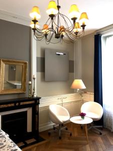 uma sala de estar com televisão, 2 cadeiras e um lustre em La Maison de famille em Boën
