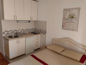 a kitchen with white cabinets and a couch in a room at Apartman Avanti in Budva