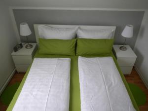 a bed with green and white sheets and two night stands at Apartment Haus Brüchert in Wernigerode