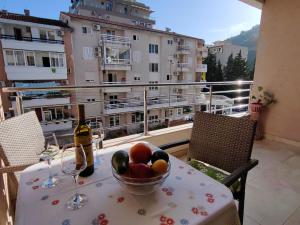 a table with a bowl of fruit and wine glasses on a balcony at Apartman Avanti in Budva