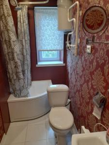 a bathroom with a toilet and a tub and a window at Quiet Summer Apartment in Aucugals