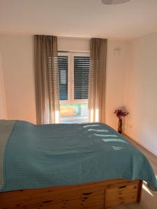 a bedroom with a bed with a blue comforter and a window at Ferienwohnung Dariana Schwalbach/Saar in Schwalbach