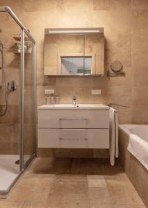 a bathroom with a sink and a tub and a mirror at Pannonia Appartements in Neusiedl am See +58 photos
