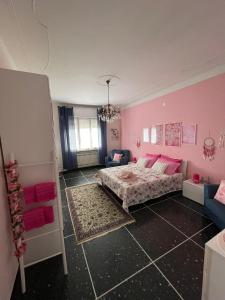 Casa Adele في سيرافالي سكريفيا: غرفة نوم وردية مع سرير وأريكة