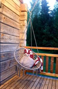 a swinging chair on a deck with a wooden fence at Villa Murmuļmuiža in Zāģeri