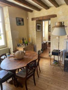 a living room with a wooden table and chairs at Domaine de La Vove - Maison d'hôtes classée, cadre paisible et naturel - ambiance insolite jardin paysager doté d'une terrasse spacieuse - une vue panoramique exceptionnelle -authenticité et élégance in Corbon