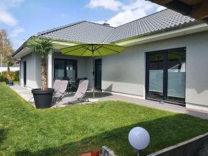 eine Terrasse mit Stühlen und einem Sonnenschirm im Hof in der Unterkunft Ruhige Wohnung mit Terrasse in Oberbrechen
