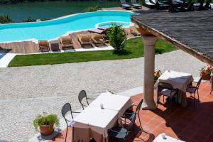 a patio with tables and chairs next to a swimming pool at Hotel Villa Cedrino in Dorgali