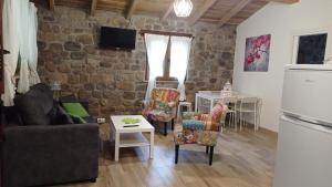 a living room with a couch and chairs and a stone wall at Apartamentos la casa de los ríos in Liérganes