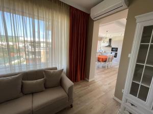 a living room with a couch and a large window at Fortuna Panorama Apartman in Odorheiu Secuiesc