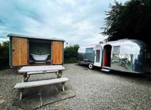 a trailer and a bench next to a table and a table at Ludlow Vintage Airstream in Ludlow