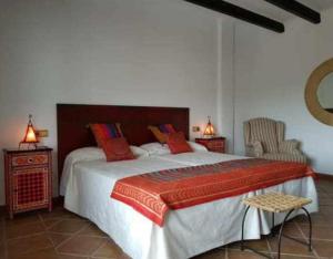 a bedroom with a large bed with red pillows at Hotel Maravedí in Pitres