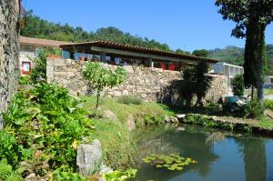 a stone house with a pond in front of it at Quinta Pedras De Baixo in Longos