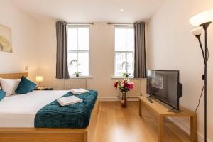 a bedroom with a bed and a tv and windows at Mansion House Apartments in London