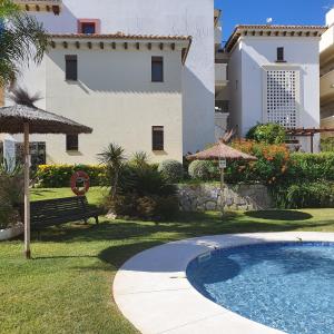 una piscina en un patio con un banco y un edificio en Costa Esuri, en Ayamonte