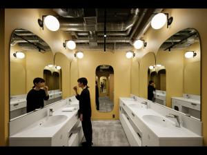 東京にあるナインアワーズウーマン新宿の洗面台付きの浴室前に立つ女性