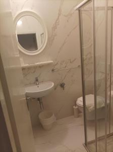 bagno con lavandino, servizi igienici e specchio di Hotel Amica a Rimini