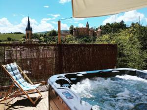 bañera de hidromasaje en una terraza con silla y sombrilla en L'ABRI du château SPA et détente, en Jarnioux