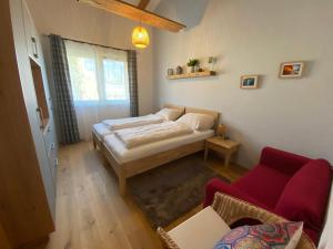 - une chambre avec un lit et un canapé rouge dans l'établissement Moderne Kaminstube, à Ramsau am Dachstein