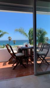 una mesa y sillas en un balcón con vistas al océano en Espectacular apartamento primera linea de playa - Golf, en Estepona