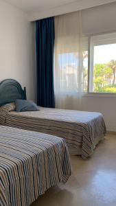 two beds in a room with a window at Espectacular apartamento primera linea de playa - Golf in Estepona