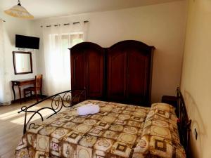 ein Schlafzimmer mit einem Bett mit einem Kopfteil aus Holz in der Unterkunft Pietra del Colle Agriturismo in Altavilla Silentina