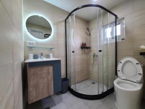 a bathroom with a shower and a toilet and a sink at Good Day Homestay in Nangan